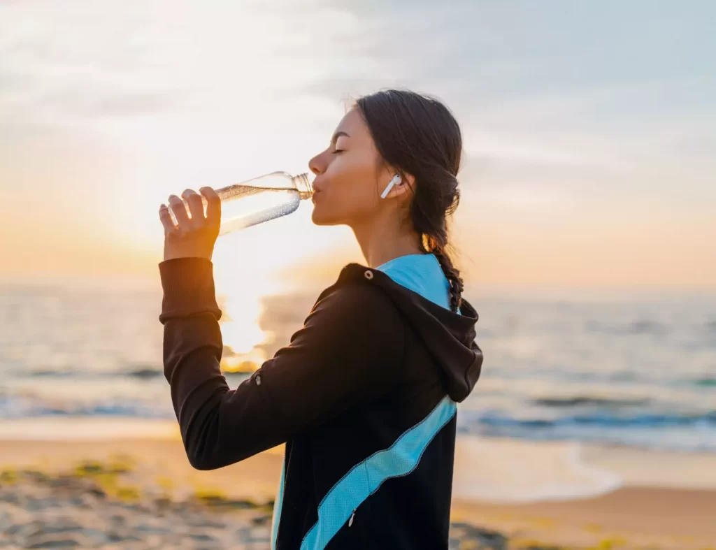 kobieta pije wodę ćwiczenia plaża morze woda