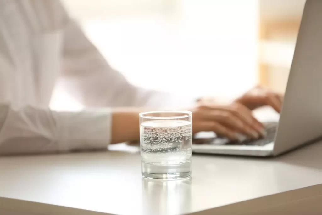 Szklanka gazowanej wody przed laptopem praca