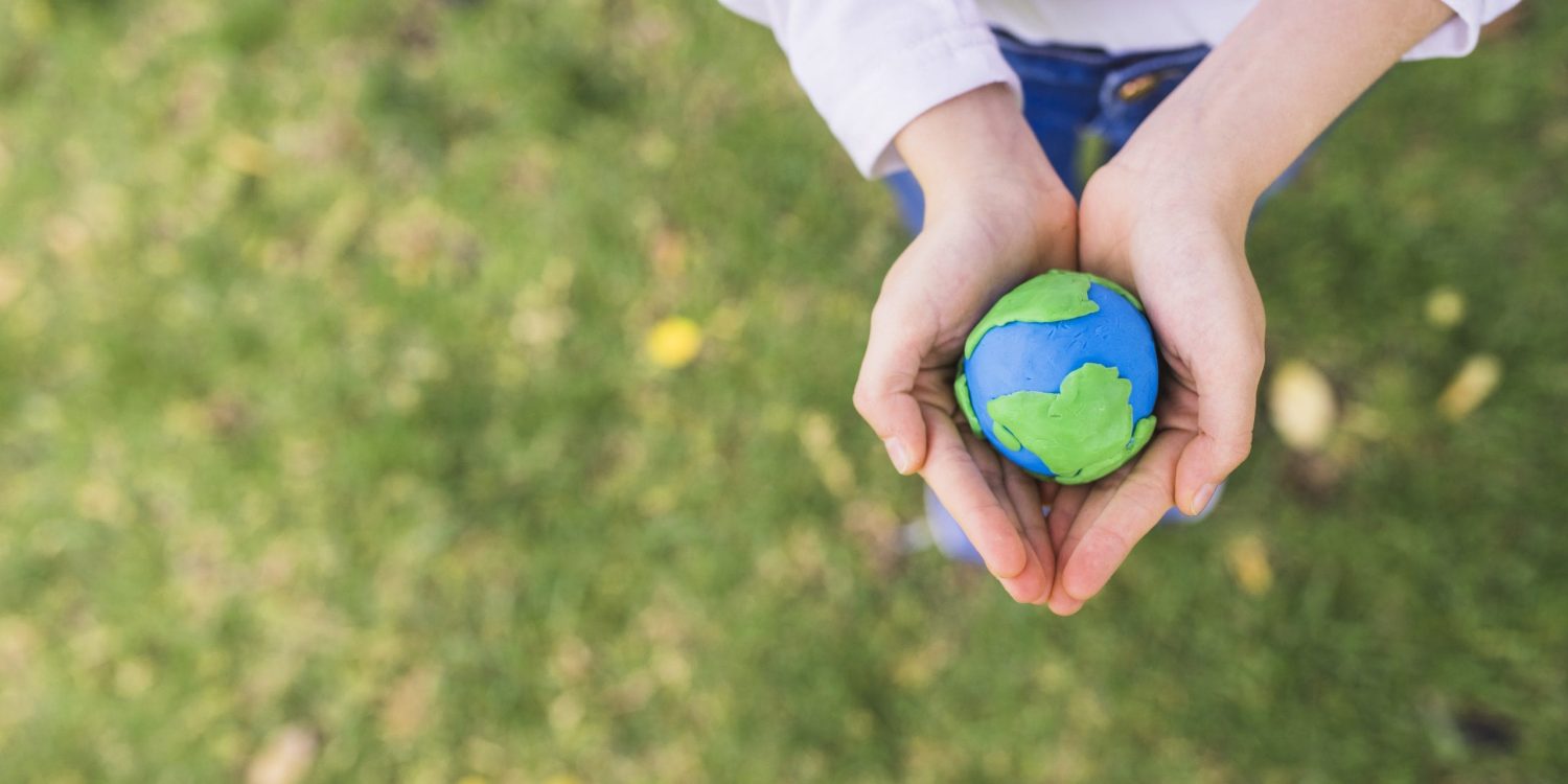 elevated-view-small-clay-globe-cupped-hands-grass ekologia ręce ziemia